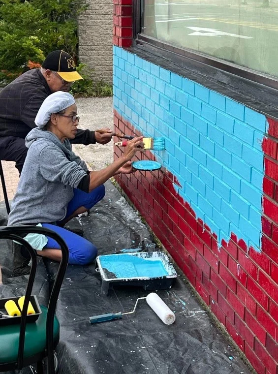 Family painting the Thai Kitchen restaurant wall together